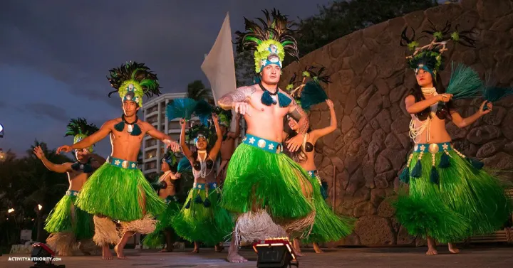 Hula dancers in green ti-leaf skirts performing at dusk at the Grand Wailea Luau in South Maui