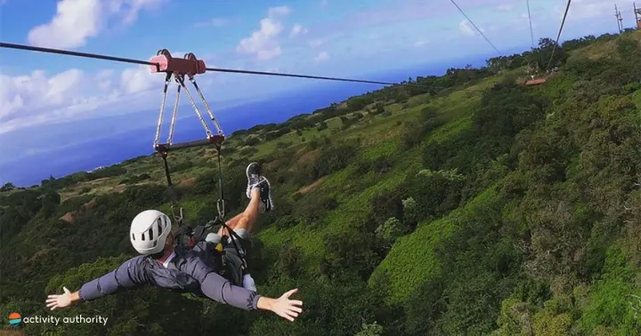 Zipliner flying arms-out over green West Maui valleys at Kapalua
