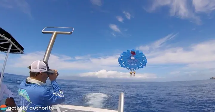 Parasail canopy flying above blue water off Kāʻanapali with a boat captain in the foreground