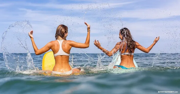 Two women splashing with surfboards in the ocean in West Maui