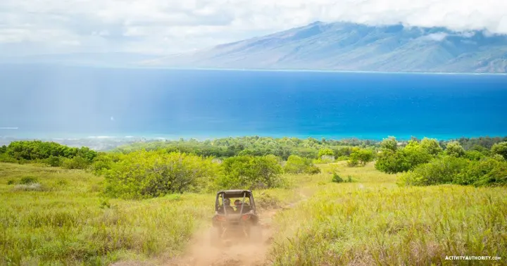 Off-road UTV kicking up dust on a West Maui mountain trail above the ocean